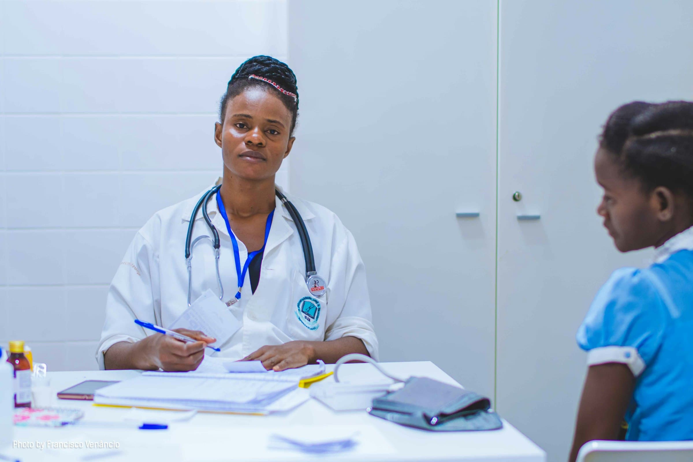 A doctor sits at a table for a consultation with a young patient, Angola.